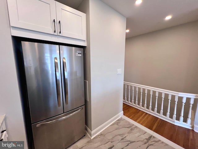 kitchen with stainless steel refrigerator, white cabinetry, and light wood-type flooring