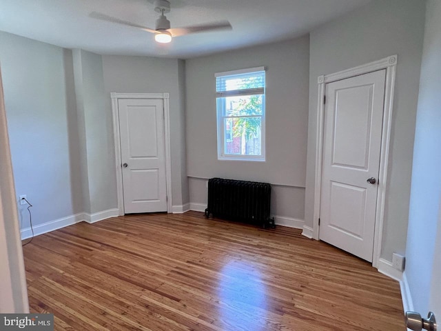 unfurnished room featuring radiator, ceiling fan, and light hardwood / wood-style floors