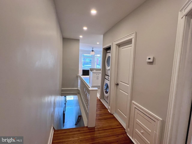 corridor with stacked washing maching and dryer and dark hardwood / wood-style floors