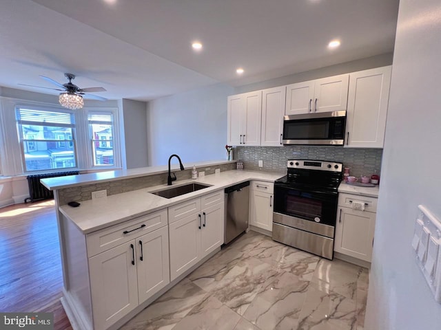 kitchen with white cabinets, kitchen peninsula, sink, and appliances with stainless steel finishes