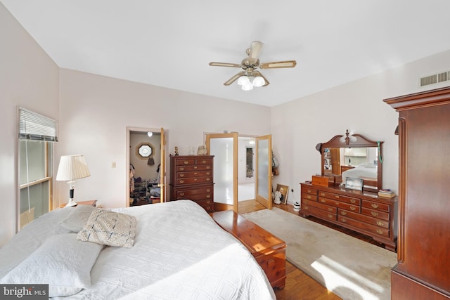 bedroom featuring a ceiling fan, visible vents, wood finished floors, and baseboards