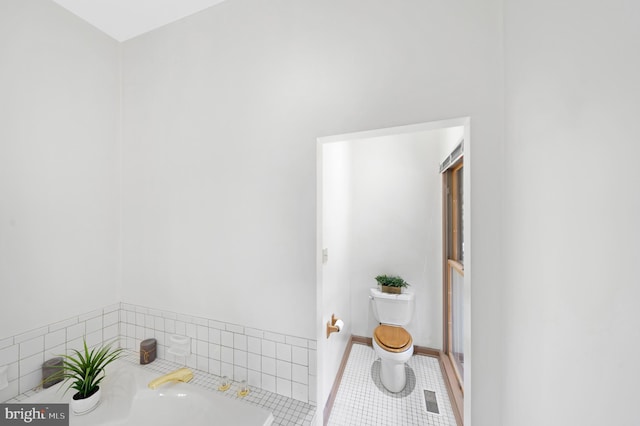 full bath featuring tile patterned floors, toilet, a bath, and baseboards