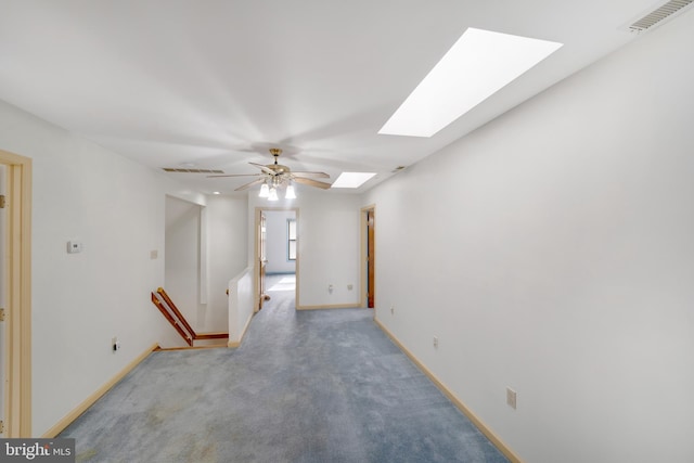 empty room featuring carpet, ceiling fan, and a skylight