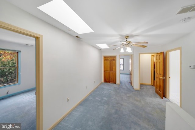 carpeted spare room featuring ceiling fan and a skylight