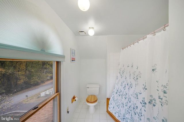 bathroom featuring a shower with shower curtain, toilet, and tile patterned flooring