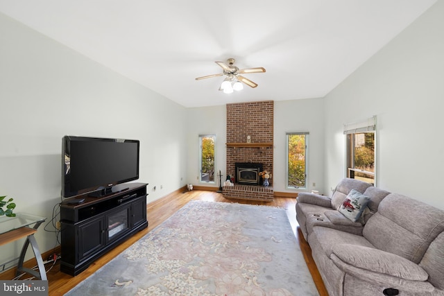 living room featuring light hardwood / wood-style floors, a wood stove, and ceiling fan