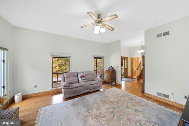 living room with light hardwood / wood-style flooring and ceiling fan with notable chandelier