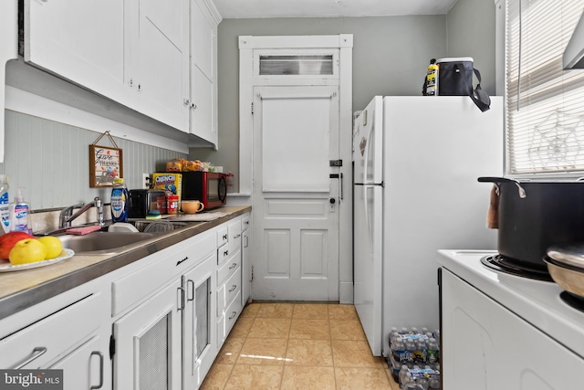 kitchen with washer / clothes dryer, sink, white cabinets, light tile patterned floors, and white refrigerator