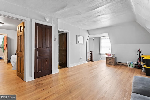 bonus room with a baseboard radiator, vaulted ceiling, a textured ceiling, and light hardwood / wood-style flooring