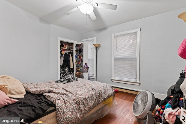 bedroom with a closet, ceiling fan, a baseboard radiator, and hardwood / wood-style floors