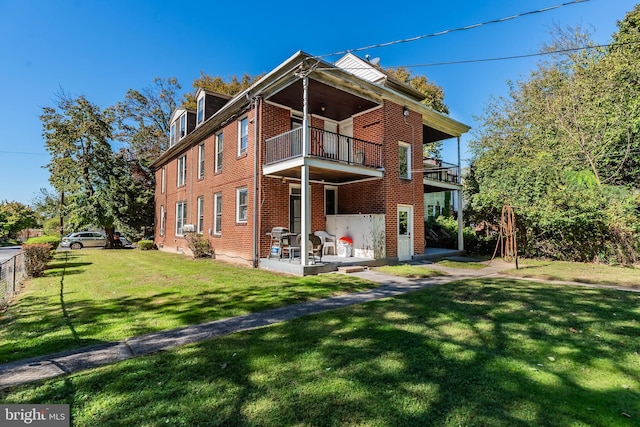 back of property with a patio, a lawn, and a balcony