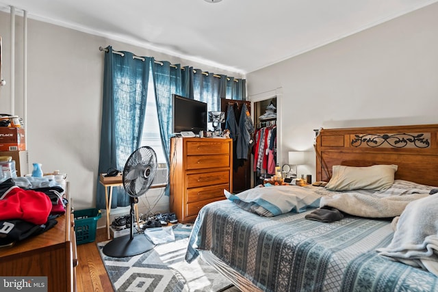 bedroom with crown molding, hardwood / wood-style flooring, and a closet