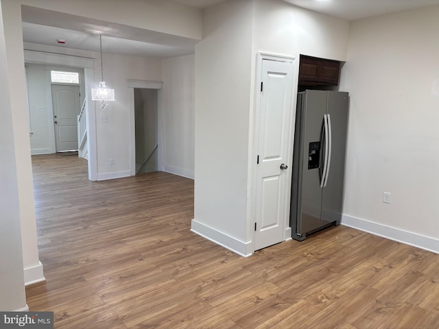 kitchen with hanging light fixtures, dark brown cabinets, light hardwood / wood-style flooring, and stainless steel fridge