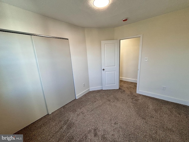 unfurnished bedroom with carpet, a textured ceiling, and a closet