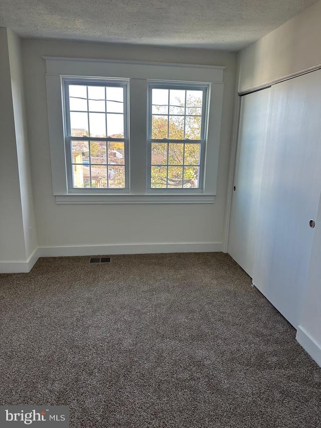 carpeted empty room featuring a textured ceiling