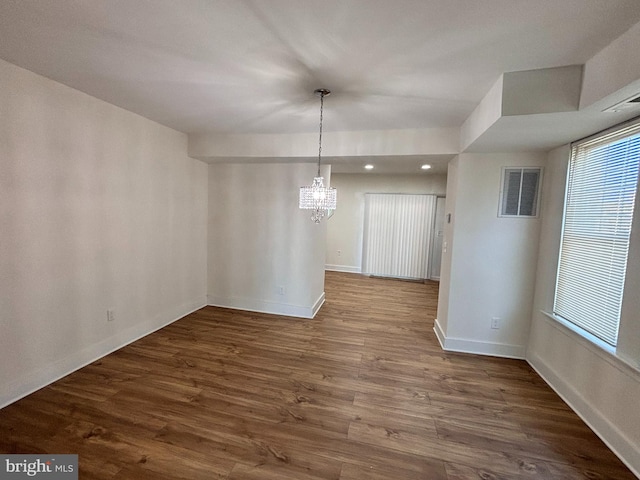 unfurnished dining area with a notable chandelier and dark hardwood / wood-style floors