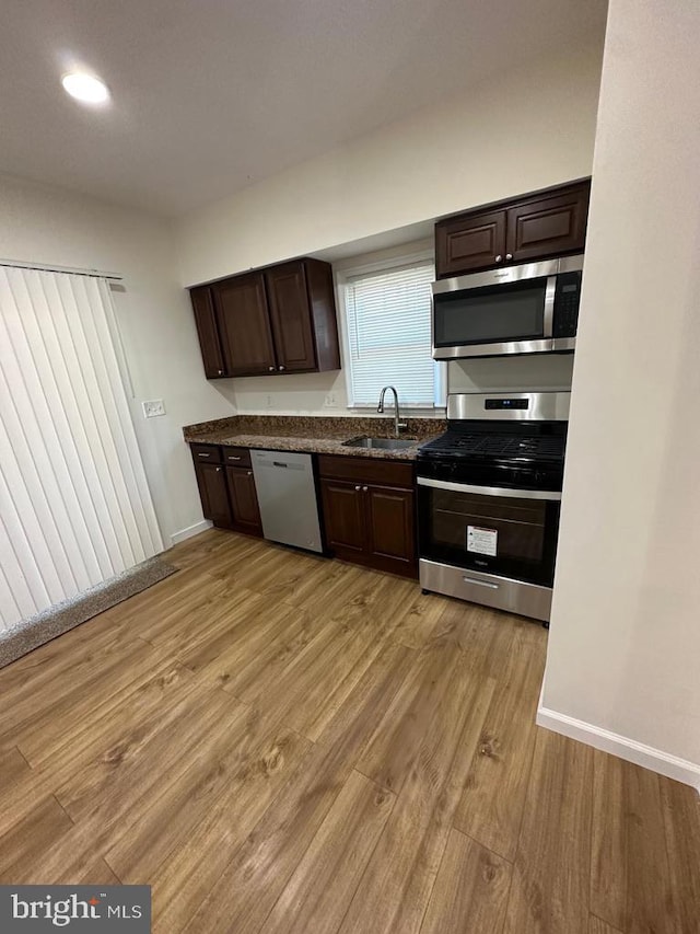 kitchen with light hardwood / wood-style floors, dark brown cabinetry, stainless steel appliances, and sink