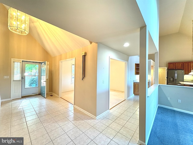 kitchen with lofted ceiling, stainless steel fridge, light tile patterned flooring, and a notable chandelier