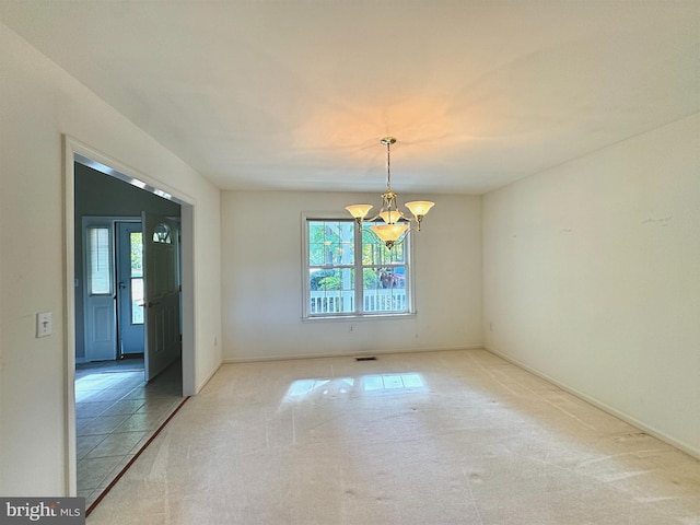 spare room featuring light colored carpet and an inviting chandelier