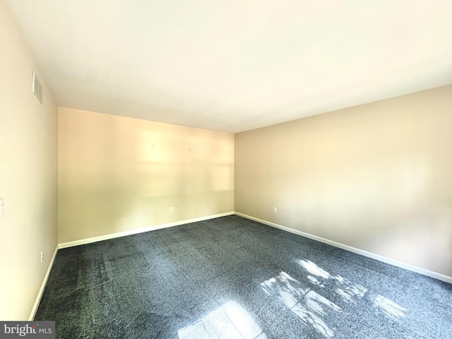 unfurnished room featuring dark colored carpet