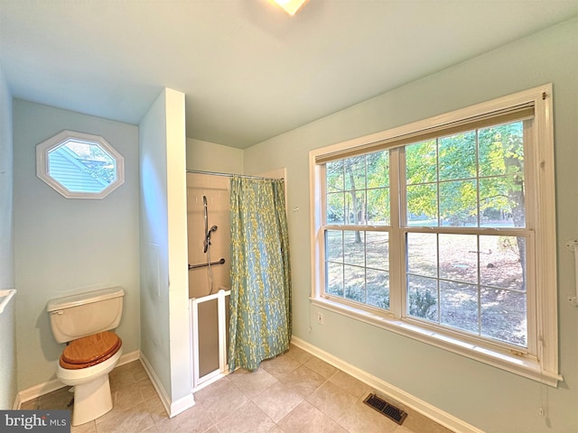 bathroom featuring toilet, walk in shower, and tile patterned flooring