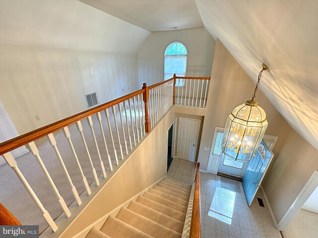 tiled entryway with an inviting chandelier and vaulted ceiling