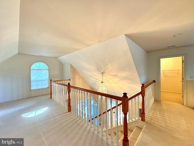 stairs with lofted ceiling, carpet flooring, and an inviting chandelier