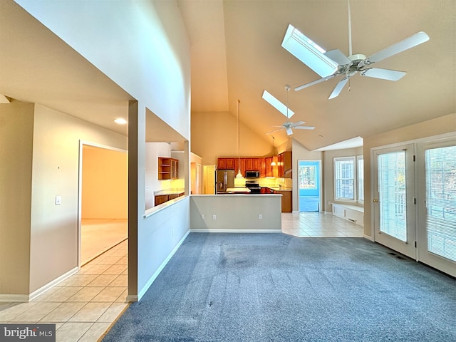 unfurnished living room featuring ceiling fan, high vaulted ceiling, a skylight, and light tile patterned floors