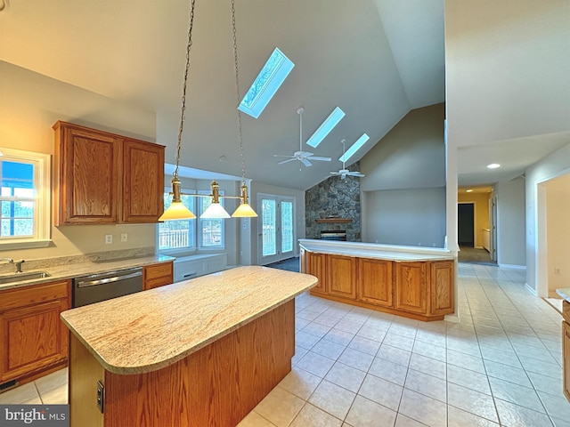 kitchen featuring a kitchen island, a stone fireplace, stainless steel dishwasher, high vaulted ceiling, and a skylight