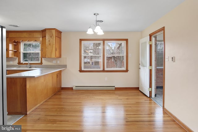 kitchen featuring pendant lighting, sink, a baseboard radiator, a notable chandelier, and light hardwood / wood-style floors