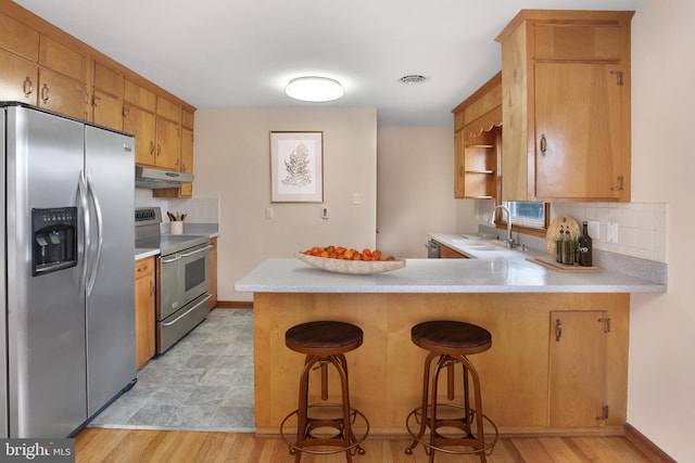 kitchen featuring kitchen peninsula, sink, a breakfast bar, and appliances with stainless steel finishes