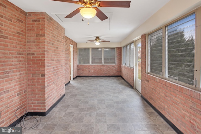 unfurnished sunroom featuring ceiling fan