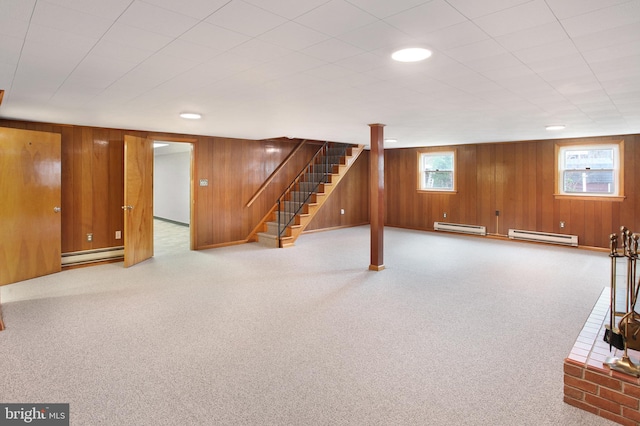 basement featuring light colored carpet, baseboard heating, and wooden walls