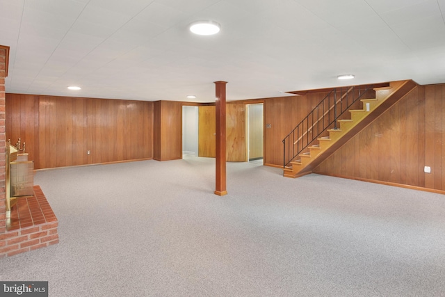 basement featuring light carpet and wood walls