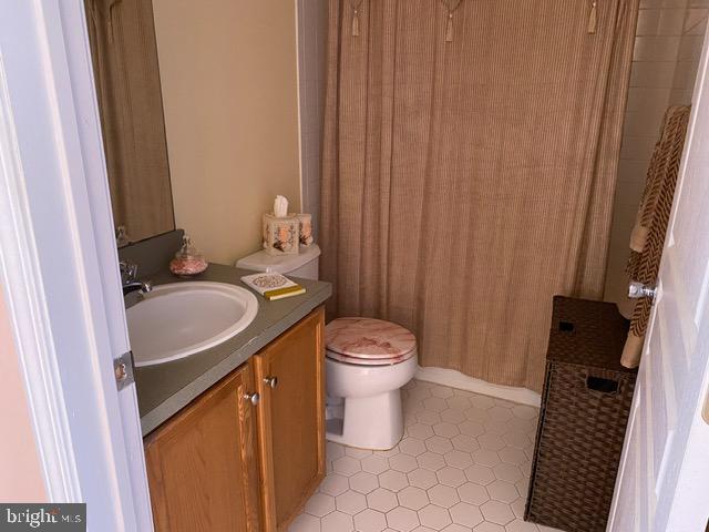 bathroom with tile patterned floors, toilet, walk in shower, and vanity