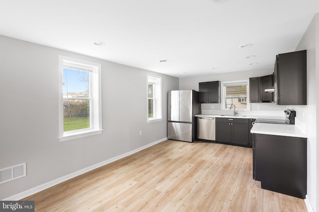 kitchen featuring extractor fan, appliances with stainless steel finishes, sink, and light wood-type flooring