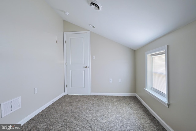 carpeted empty room with vaulted ceiling