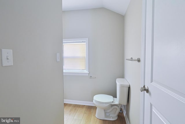 bathroom featuring toilet, hardwood / wood-style flooring, and vaulted ceiling