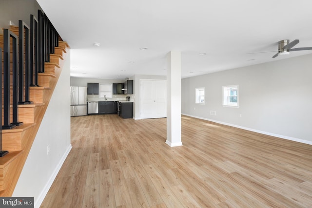 unfurnished living room with light hardwood / wood-style flooring, sink, and ceiling fan