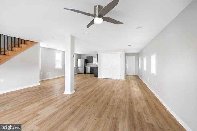 unfurnished living room with sink, ceiling fan, and light hardwood / wood-style flooring