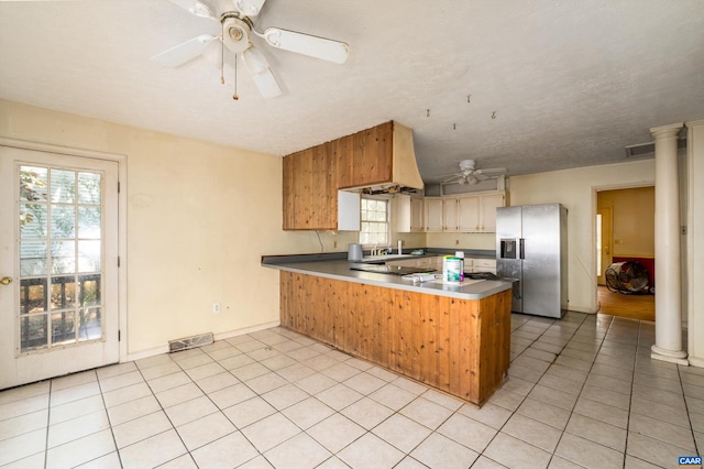 kitchen featuring light tile patterned flooring, kitchen peninsula, a textured ceiling, stainless steel refrigerator with ice dispenser, and decorative columns