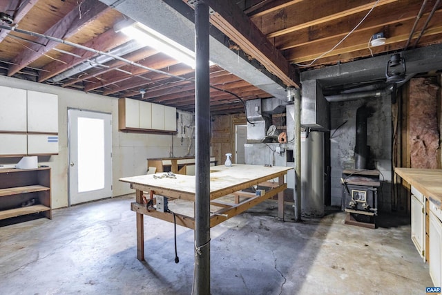 basement with a workshop area, water heater, and a wood stove