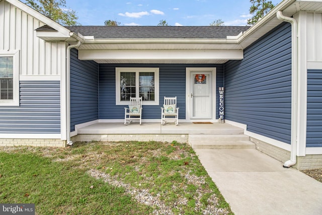 view of exterior entry featuring a yard and covered porch