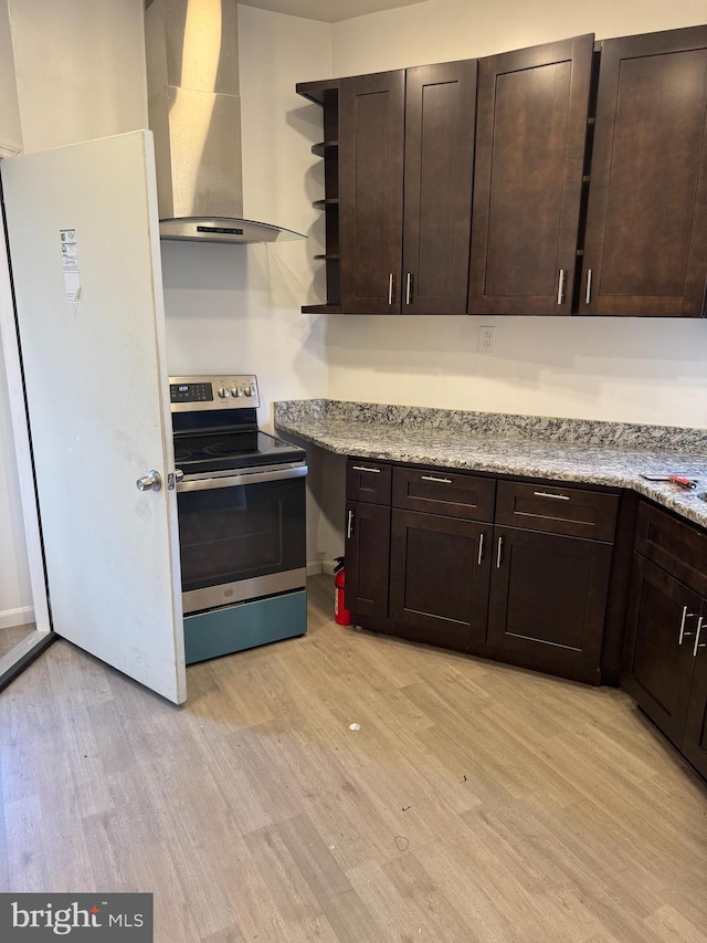 kitchen with dark brown cabinetry, stainless steel electric range oven, light hardwood / wood-style floors, and range hood