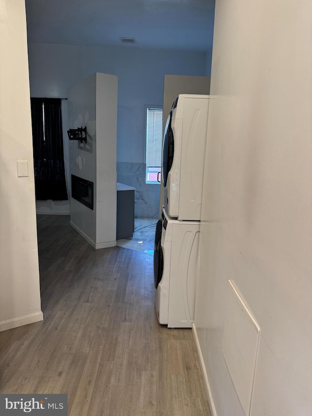 hallway featuring hardwood / wood-style flooring and stacked washer / dryer