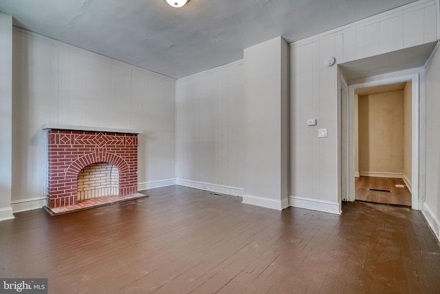 unfurnished living room featuring a brick fireplace and dark wood-type flooring