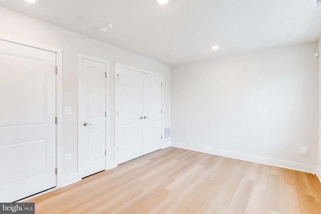 unfurnished bedroom featuring light hardwood / wood-style flooring and two closets