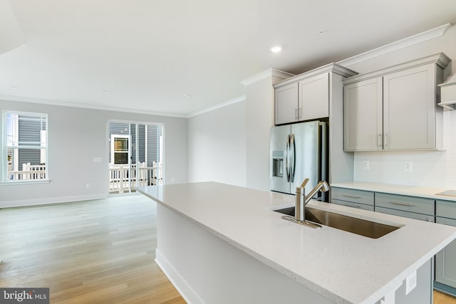 kitchen with a center island with sink, stainless steel refrigerator with ice dispenser, light hardwood / wood-style flooring, and gray cabinetry