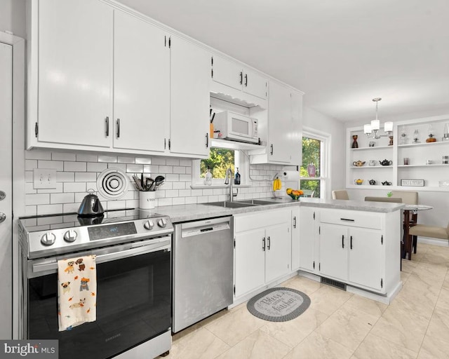 kitchen with white cabinetry, decorative light fixtures, stainless steel appliances, and backsplash