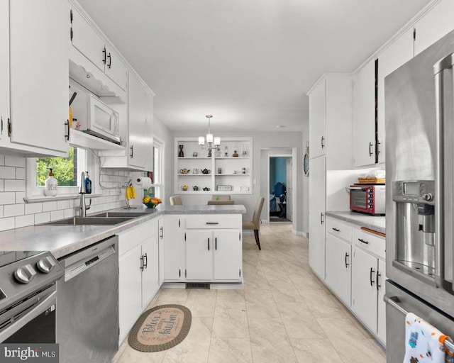 kitchen with hanging light fixtures, appliances with stainless steel finishes, and white cabinets